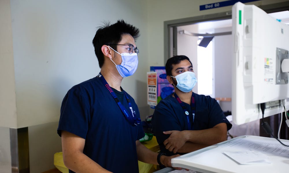 Two staff look at a screen