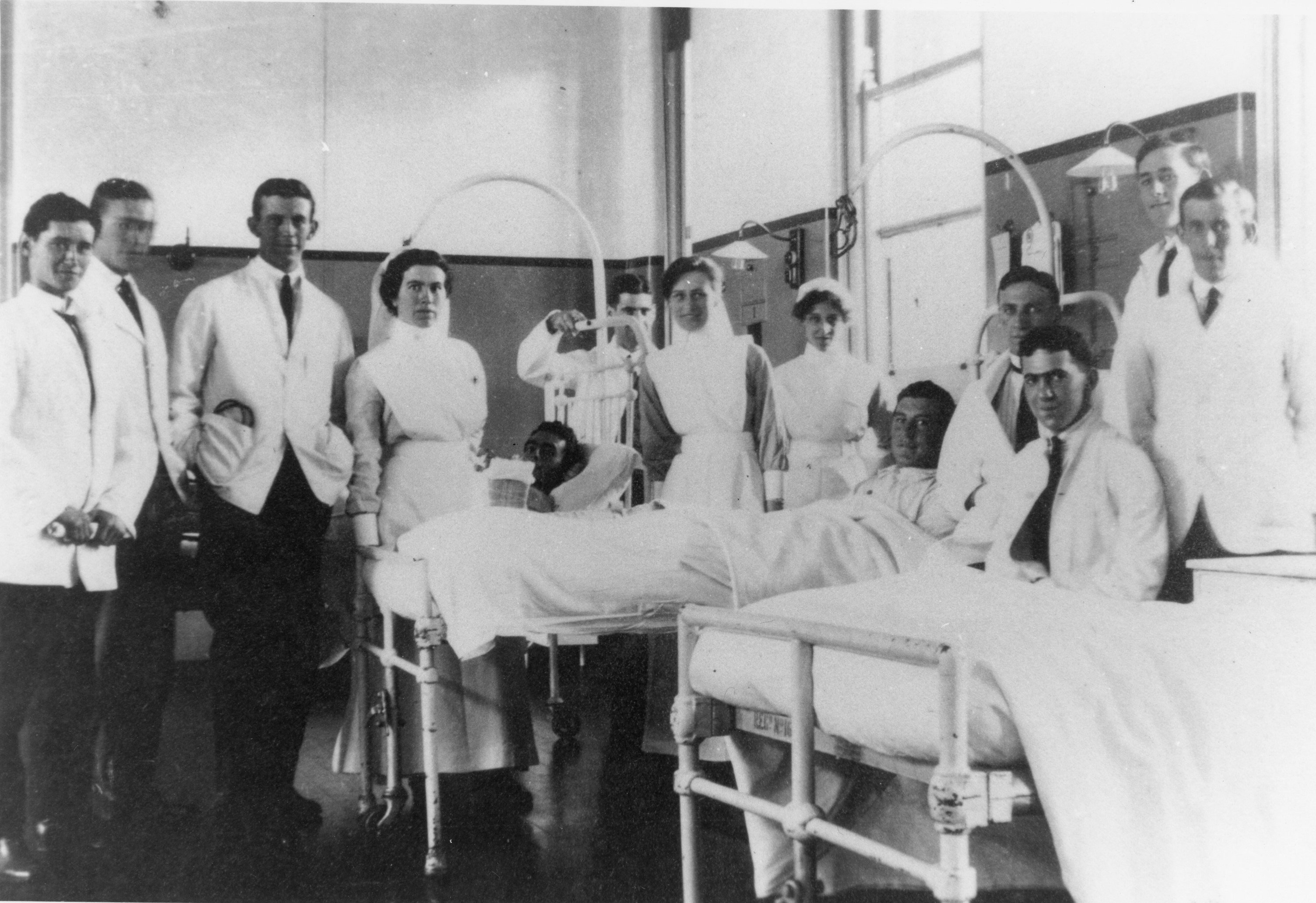 1920s ward scene of medical nurses by male patients' bedside