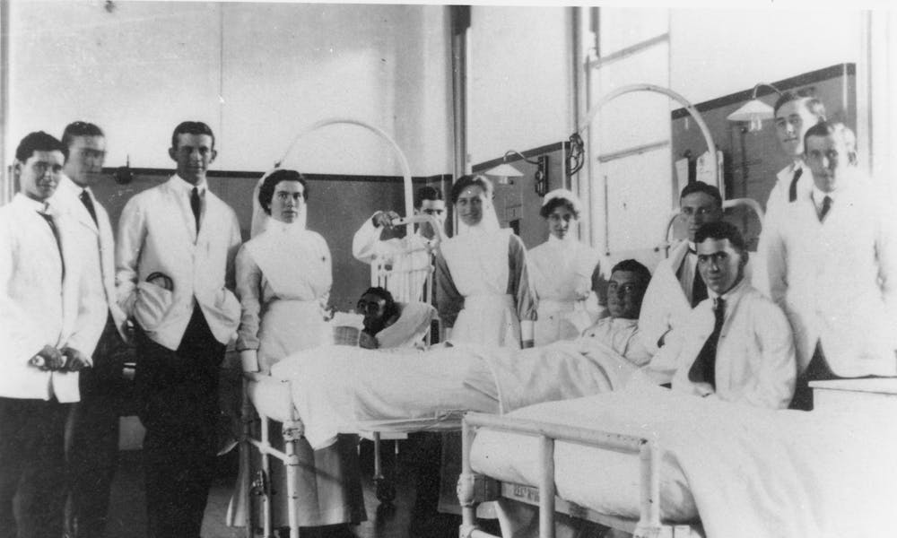 1920s ward scene of medical nurses by male patients' bedside