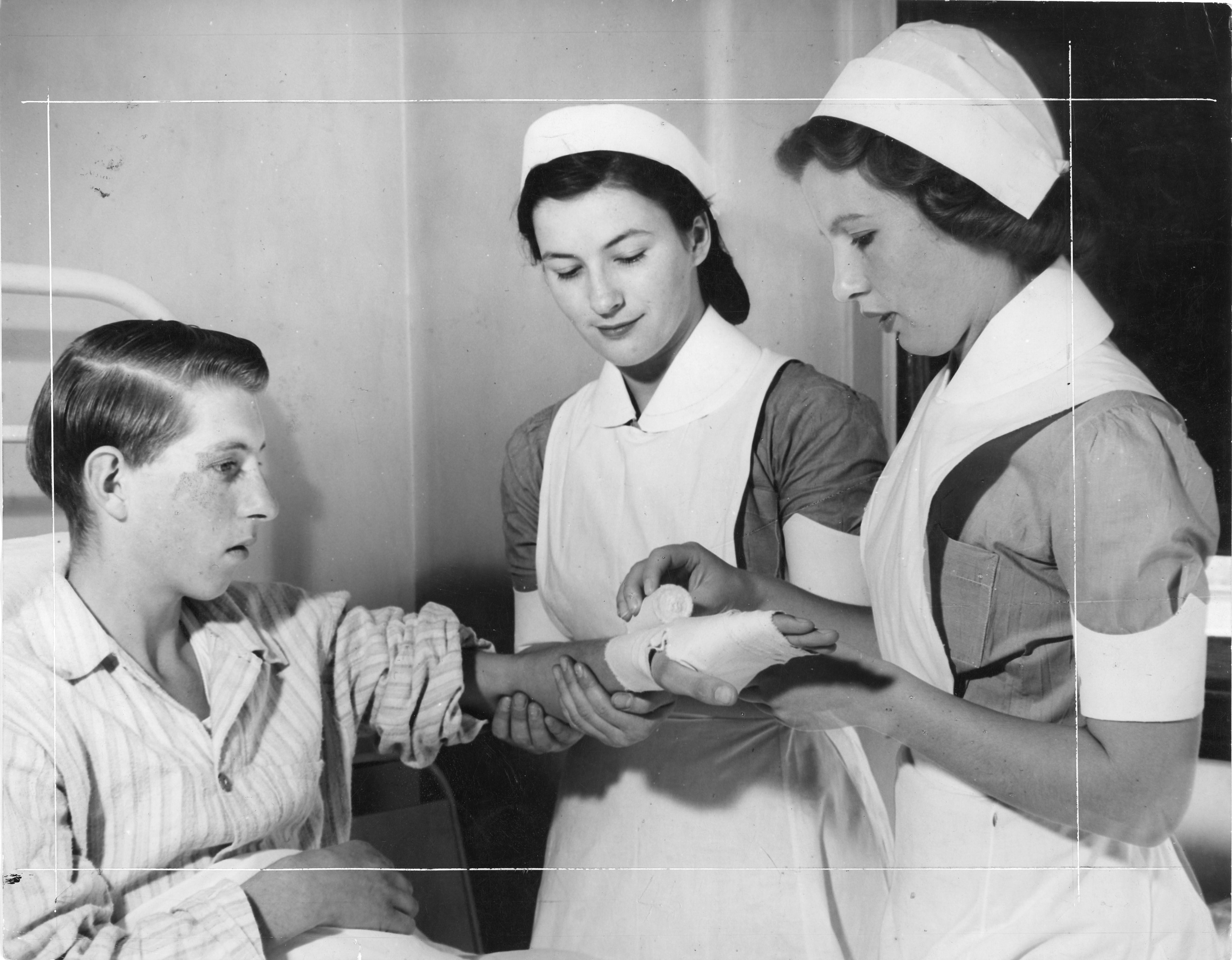 Two student nurses practising bandaging on a patient in 1948