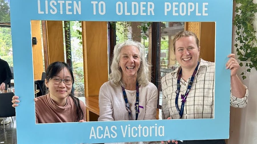 Three women holding sign that says 'Listen to older people - ACAS Victoria'