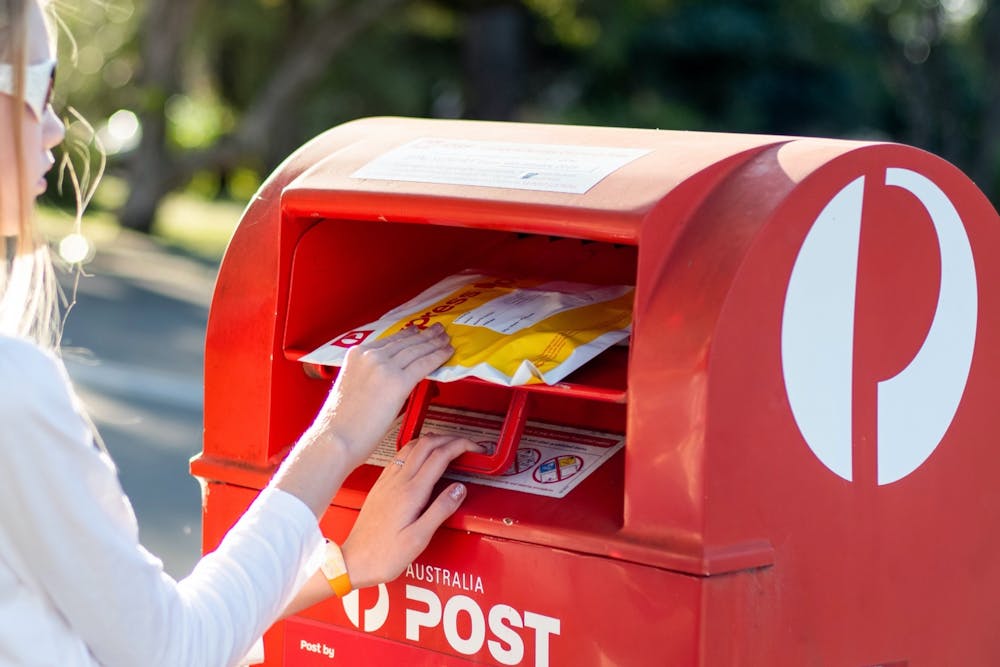 Girl posting an Express Post parcel in an Australia Post box