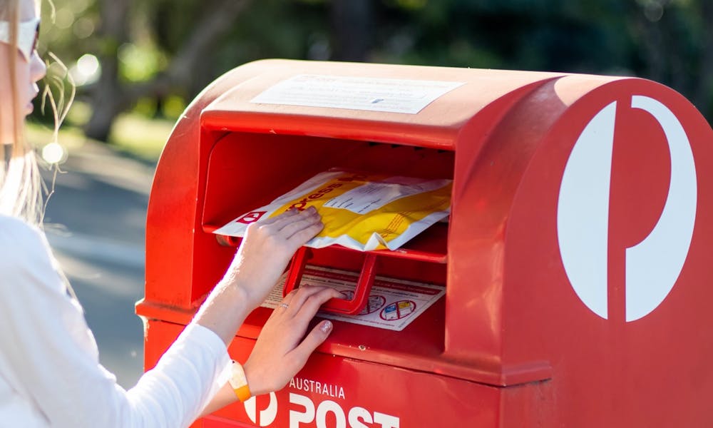 Girl posting an Express Post parcel in an Australia Post box