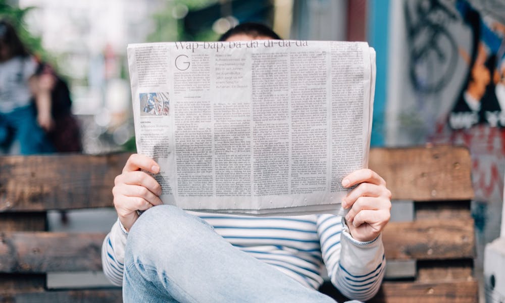 Man reading newspaper outside