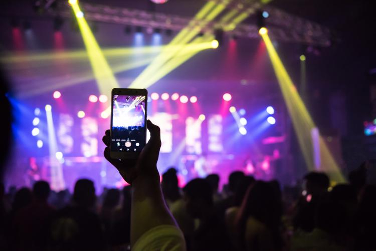 Hand using phone to take photo of stage at music festival