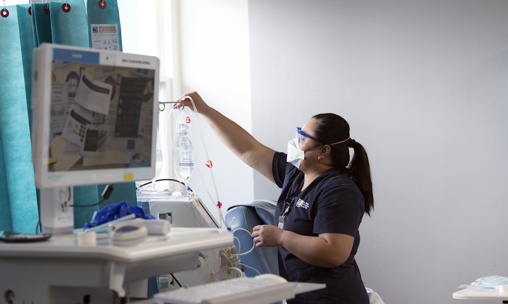 Dialysis nurse replacing IV bag for patient