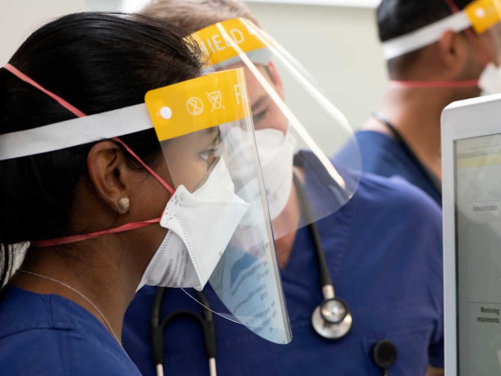 ICU staff in masks and shields looking at computer