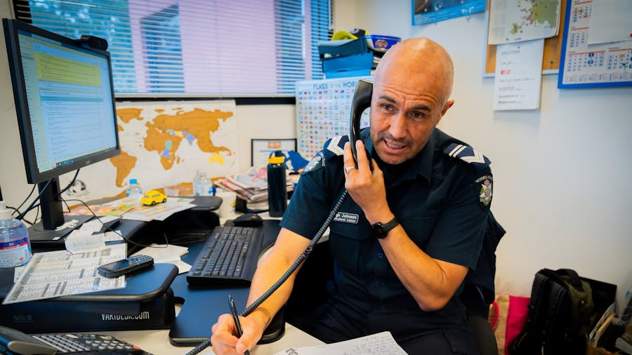 Male police officer on office phone taking notes (Image copyright Victoria Police)