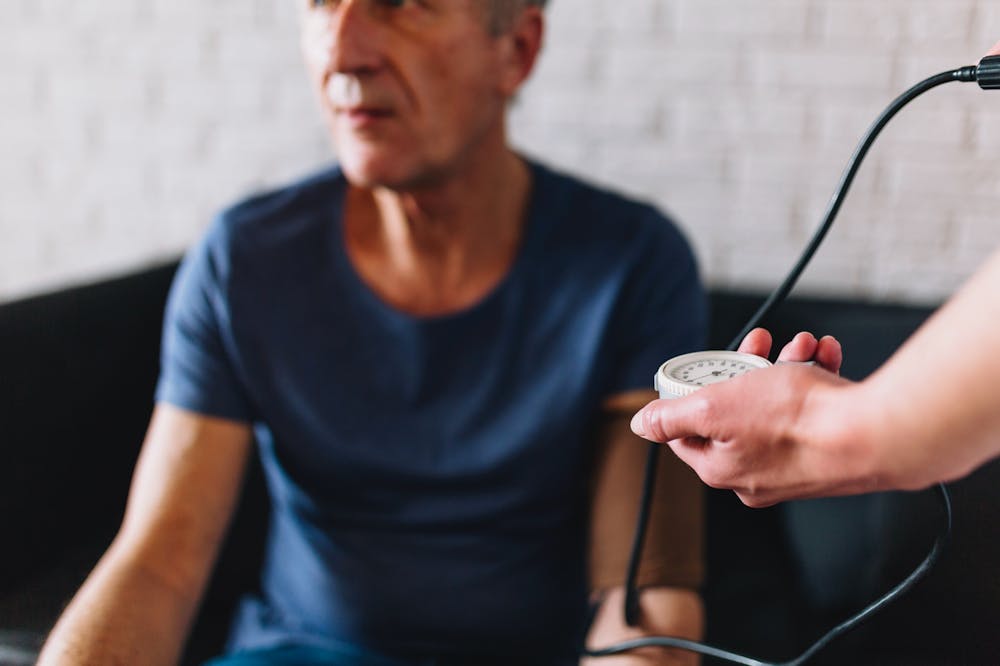 Man in retirement home with nurse using stethoscope
