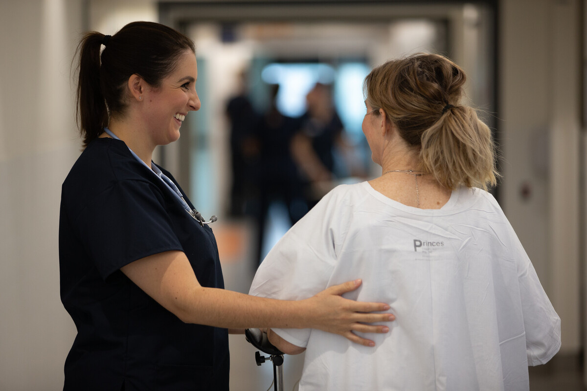 Nurse guides patient down hallway