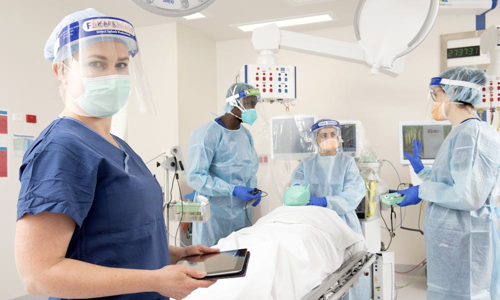 Four nurses in PPE training in a simulated hospital room