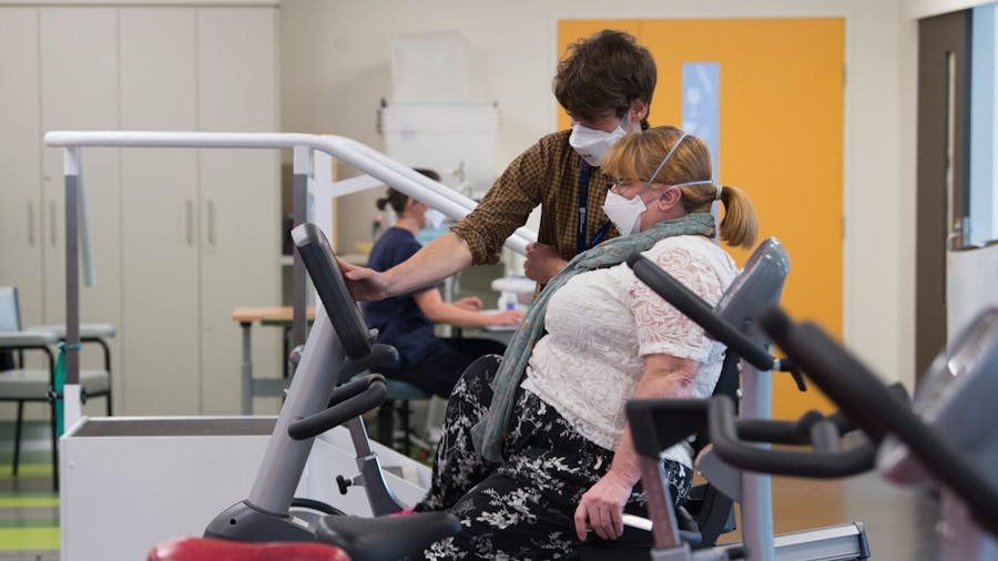 Physiotherapist helping patient with exercise bike in physio gym