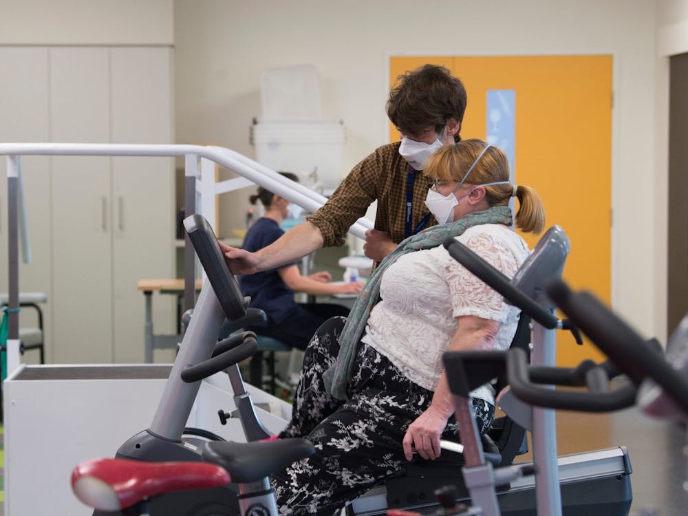 Physiotherapist helping patient with exercise bike in physio gym