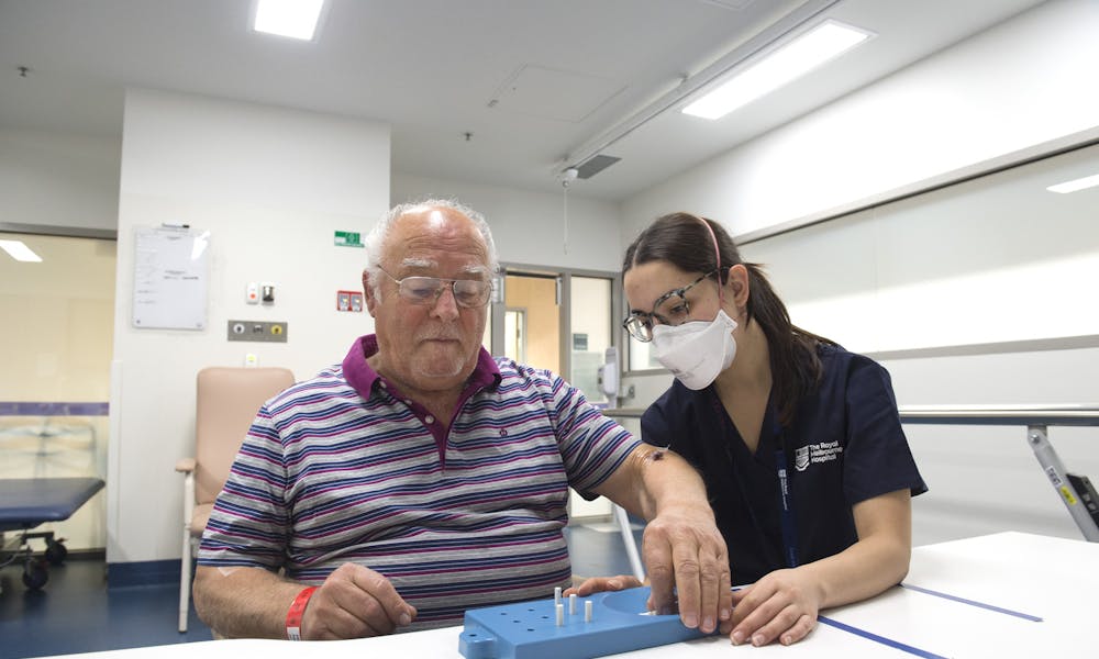 Neurology and Stroke staff member and patient placing pegs into hole